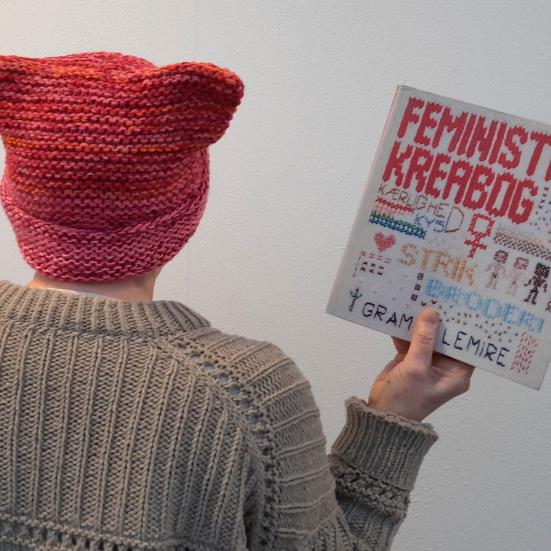 Person set bagfra med strikhue og trøje og kreabog i hånden